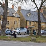 Yellow-stone shops, with trees in front.