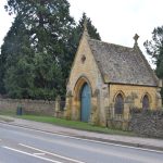 A small yellow-stone lodge across a quiet road, with dry-stone walls either side.