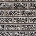 A stone wall made of of large stones. Each has intricate detailing, with larger and smaller dimples in the stone.