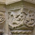 A stone carving of centaurs fighting, on a light stone block around a corner.