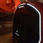 A mock-up of the front of a Tube train, with lit white text reading “Heathrow”, “256” and “PICCADILLY LINE”. The train has a white border around the edge of its black front, and the visible sides are red. Behind are other displays in a museum, including an orange formed plastic object whose function is not apparent.