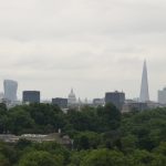 A view of the skyline of London. The Walkie Talkie, St Paul’s and the Shard are visible. The foreground is tree cover.
