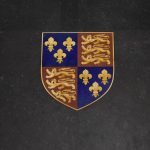 A detailed mosaic of the Plantagenet coat of arms inlaid into dark stone.
