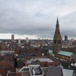 An elevated view of a city centre, the most prominent building being a cathedral with a high tower and spire.