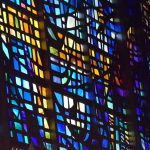 A close-up of a modern, abstract stained glass window, in bright primary colours.