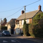 A pub and a thatched-roof barn, on a residential street.