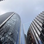 Several curved and rectangular office buildings, mostly faced with glass, beneath a grey sky.