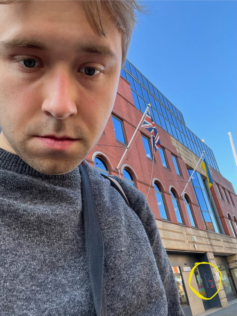 The same photo of the blog's author in front of a building, but with a yellow circle hand-drawn around the council's logo. It doesn't really help.