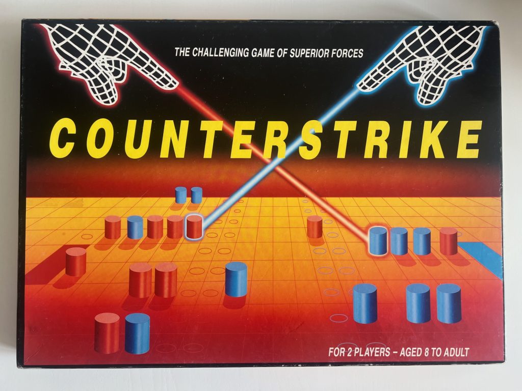 A box for a board game called "Counterstrike". The name is across the centre of the box in block-caps yellow type. Above it, smaller and in white, it says "The challenging game of superior forces", and at the bottom right it says "For 2 players – aged 8 to adult". The box art shows a grid in a perspective view, coloured with a red-yellow gradient; above the top row of the grid, the background is plain, coloured with a black-red gradient. The grid at the bottom is dotted with red and blue cylinders; also, some of the spaces have circles printed on them, and two spaces on each side are filled in in block colour (red on the left, blue on the right). In the sky are two wireframe hands, shown with a white lines, and glowing red (on the left) and blue (on the right). The hands are pointing at the board, and out of each index finger a glowing beam of coloured light is shooting at one of the cylinders of the opposite colour; the beams cross in midair above the board. The pieces being hit by the light beams are themselves glowing.